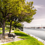 The Fox River in Green Bay, featuring calm waters, green riverbanks, and historic buildings in the background.