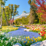 The Grand Hotel on Mackinac Island, showcasing its grand facade, long porch, and lush gardens with vibrant flowers.