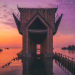 Sunset view of Lower Harbor Ore Dock, with vibrant sky colors reflecting on the water and the historic dock in silhouette.