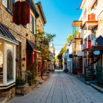 Rue du Petit Champlain, featuring charming shops and cafes, cobblestone streets & colorful buildings with vibrant decor.