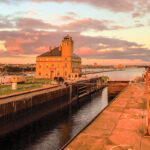 The Soo Locks, featuring the lock system, surrounded by calm waters and green landscapes.