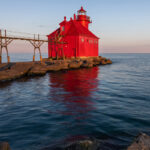 Sturgeon Bay Ship Canal Pierhead, featuring the lighthouse at the end of the pier with calm waters and a clear sky.