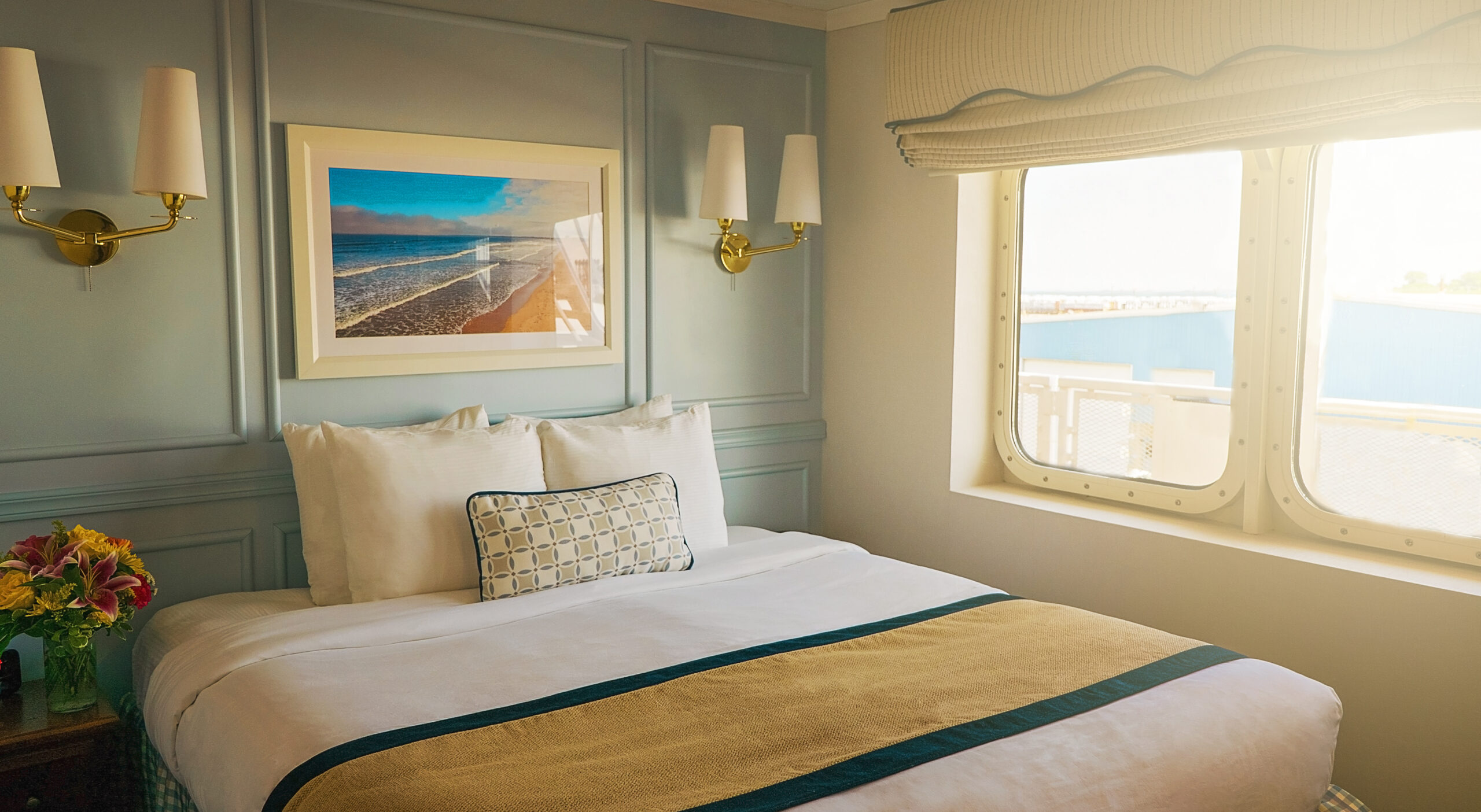 A picture of a stateroom on the Victory cruise ship, showing a neatly made bed in a quaint room.