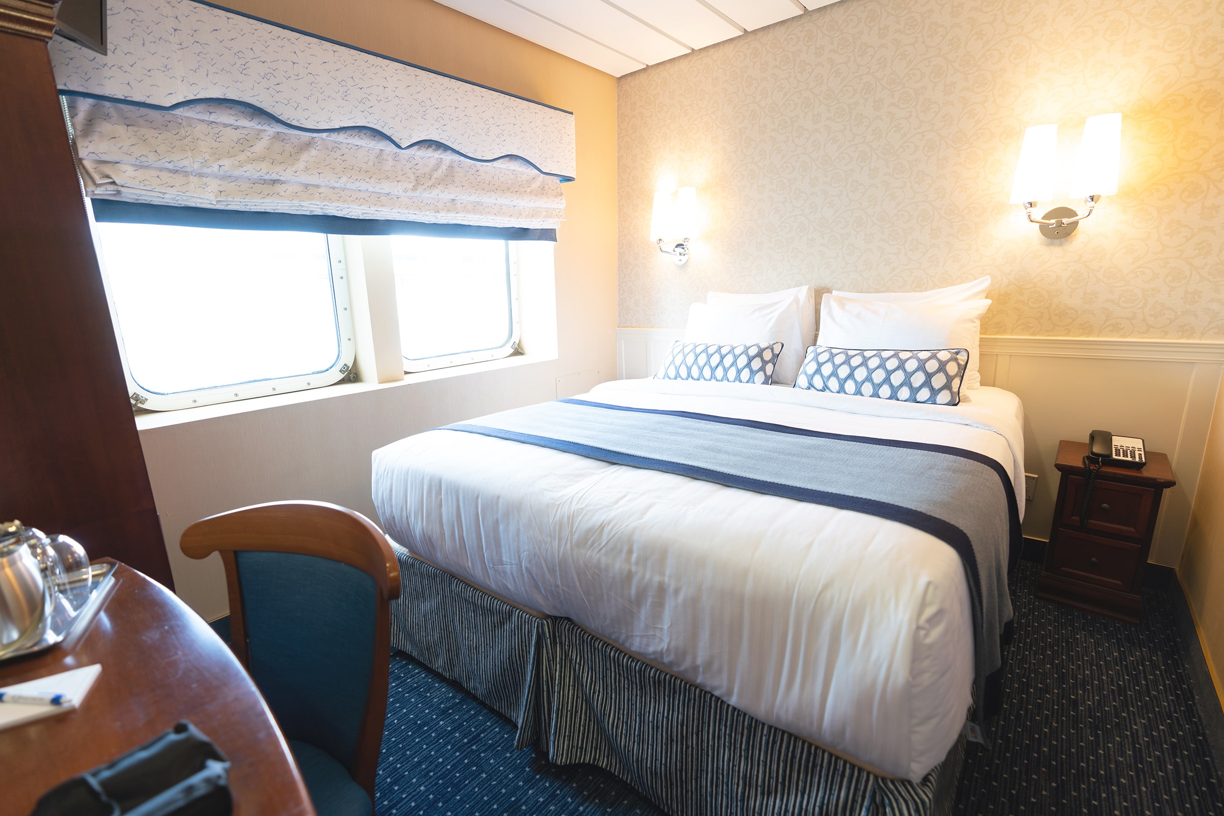 A picture of a Victory Cruise Line interior stateroom with a cozy queen bed, bathroom and in-suite entertainment.