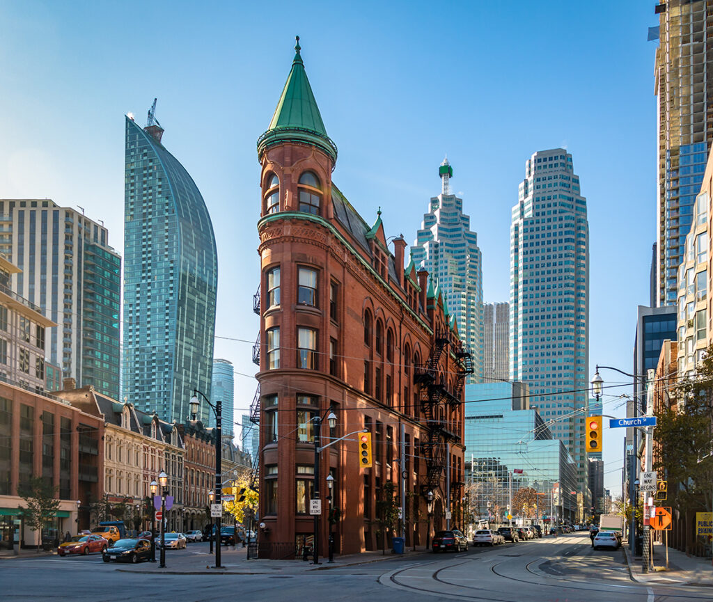 A view of the Flatiron Building in Toronto, featuring its distinctive triangular shape and historic red-brick façade.