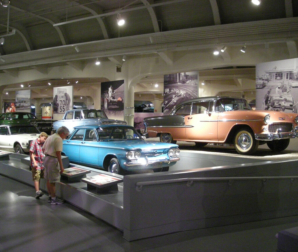 A picture of the Henry Ford Museum, featuring a display of classic cars, with vintage vehicles arranged in an exhibit.