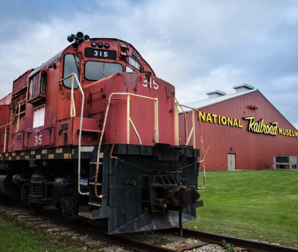 A picture of the Wisconsin Railroad Museum, featuring historic train engines and carriages displayed.