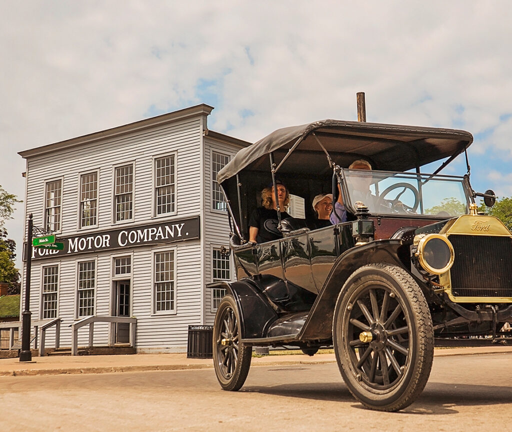 A Ford Model T parked in front of the historic Ford Motor Company building, showcasing the classic car's vintage design.