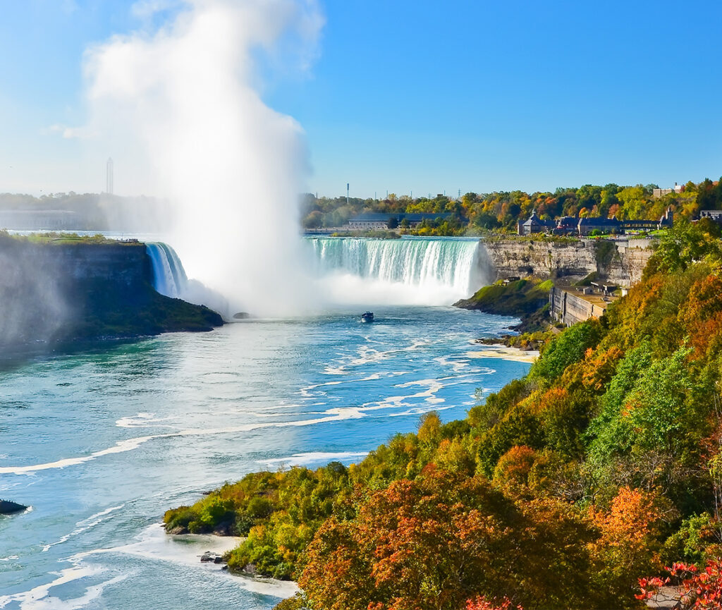 A dramatic view of Niagara Falls, with powerful waterfalls creating a thick mist that rises up.