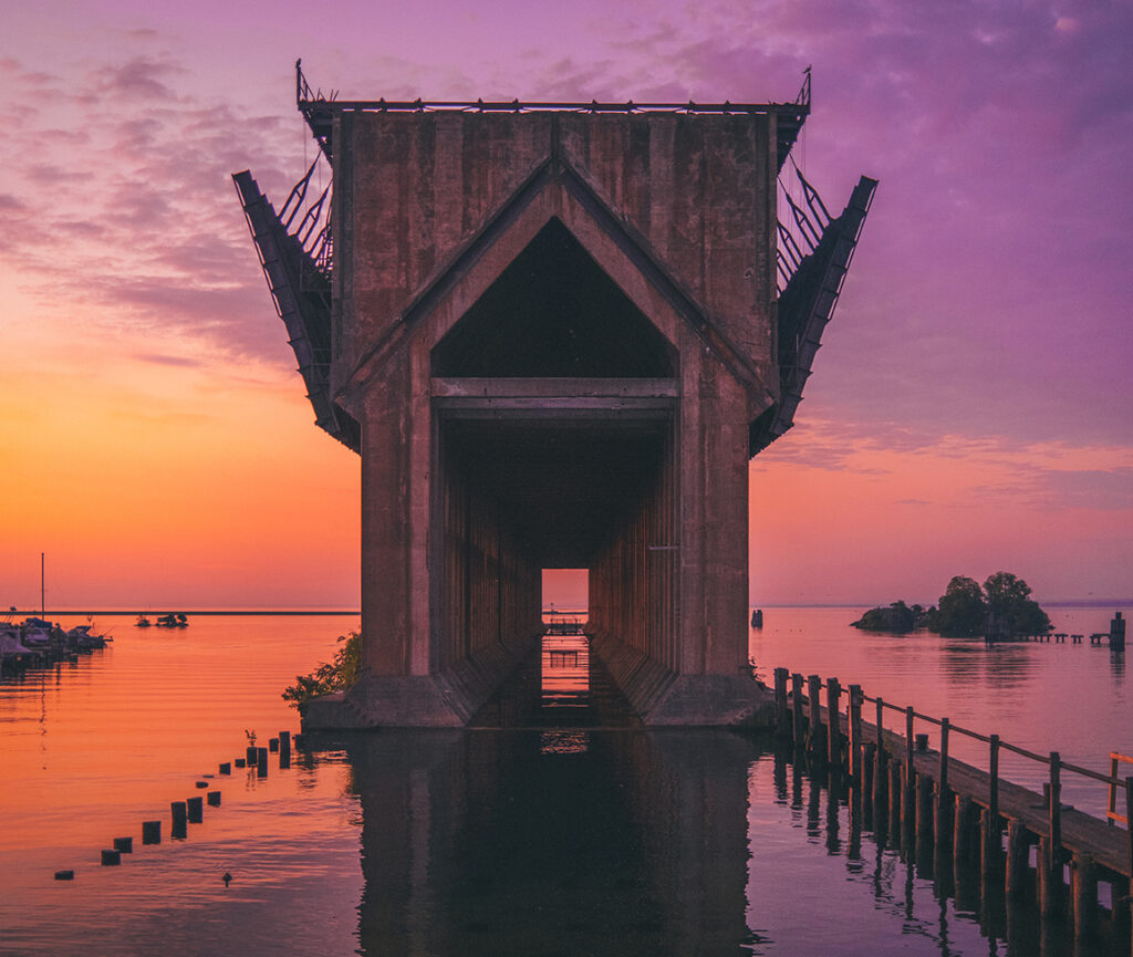 A sunrise view of Marquette Ore Dock, with the sky painted reflecting on the calm waters of Lake Superior